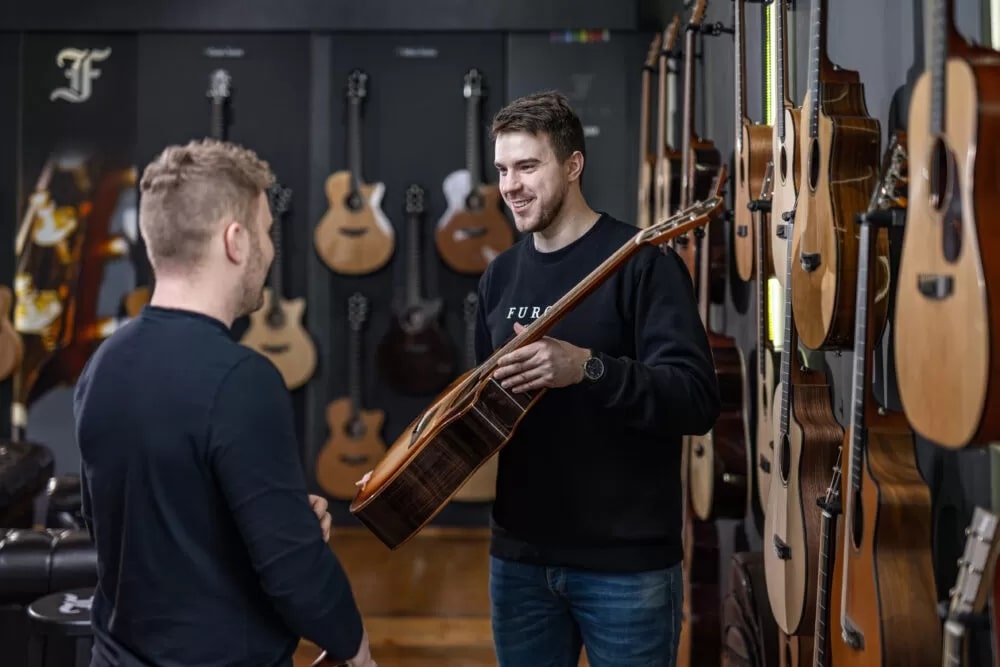 Prodejce ukazuje kytaru Furch zákazníkovi v přímo ve firemní prodejně